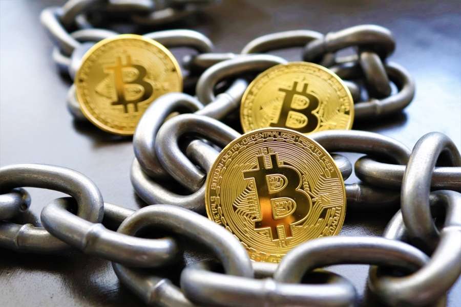 Des pièces de Bitcoin dorées entrelacées dans une chaîne métallique, symbolisant la sécurité des smart contracts.